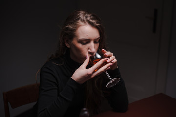 Fototapeta na wymiar Young beautiful woman in severe depression, drinking alcohol. The concept of abuse and alcoholism. Alcoholic woman drinking from a bottle and glass of wine. Selective focus on glass.