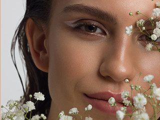 Close up half portrait of a face with beautiful skin and nude makeup, eyeliner and long eyelashes,...