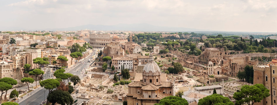 Aerial panoramic cityscape view of the Roman Forum and Roman Colosseum in Rome, Italy. World famous landmarks in Italy during summer sunny day. Heritage Unesco historical buildings.