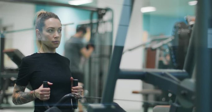 woman exercising with rowing machine at gym.Front view, slow motion. Woman training at rowing machine