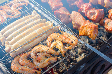 fresh juicy shish kebab sausages and prawns fried on coals on a barbecue in the backyard