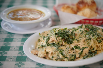 Spinach chicken pasta white sauce with garlic rolls and soup on the table