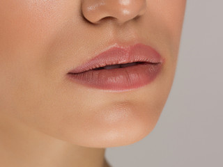 Fototapeta premium Sexual full lips. Natural gloss of lips and woman's skin. The mouth is closed. Increase in lips, cosmetology. Natural lips. Great summer mood with open eyes. fashion jewelry. Pink lip gloss