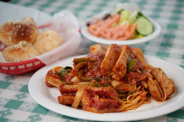 Sausage pasta served on the table with garlic rolls and salad