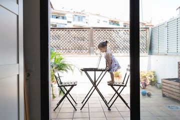 A little girl looks a laptop at home