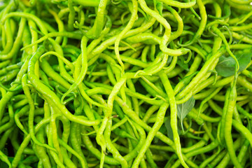 fresh thin hot green peppers laid out on the counter for sale in the organic market