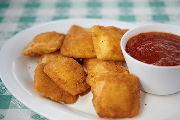Fried ravioli on white plate with marinara sauce