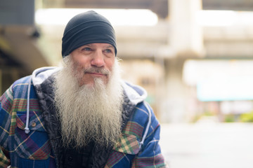 Face of mature handsome bearded man thinking in the city outdoors