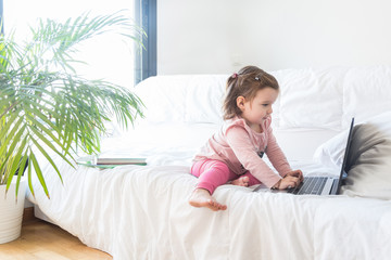 illte girl playing with laptop at home