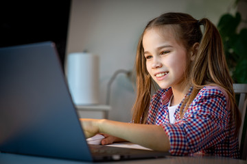 teen girl makes lessons, homework on laptop.