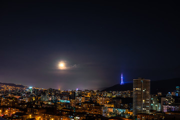 Moon rising and stars in night sky over Tbilisi