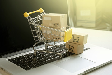 shopping cart with parcels standing on laptop. Online shopping concept
