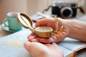Fototapeta na wymiar Vintage compass in female hands. Young woman planning her vacation with travel map, looking for next destination. Wanderlust, globetrotter trends, adventure and holiday concept. Focus on compass.