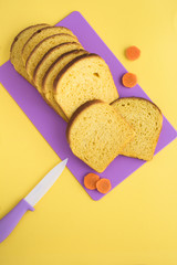 Homemade carrot bread on the violet cutting board on the yellow background. Location vertical. Top view.
