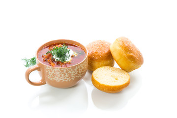hot beetroot soup with sour cream, herbs and rolls in a ceramic bowl