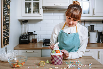 A gloved cook sticks a ginger cookie shaped like an Easter Bunny into the icing of an Easter cake