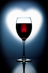 
Glass goblet with red wine on a gradient background in the form of a heart