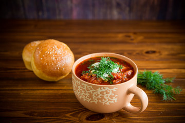 hot beetroot soup with sour cream, herbs and rolls in a ceramic bowl