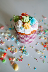 Easter cake with sweet figures on the glaze, standing on the kitchen table, which is strewn with sweet ingredients