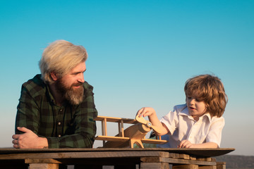 Father and son playing with toy airplane at sunset. Friendly man family. Family holiday and togetherness. Father and son together. Happy child playing with toy plane against summer sky background.