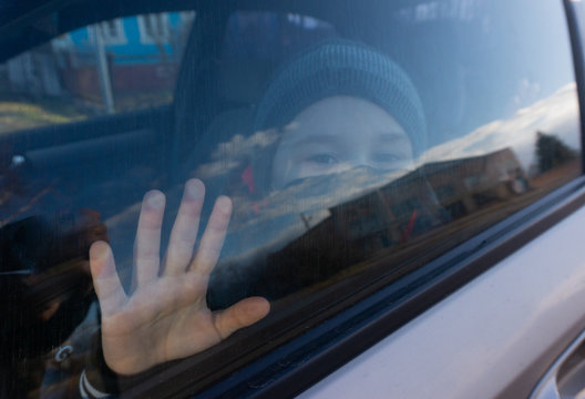 A Boy In A Black Mask Behind A Car Window