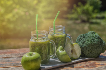Healthy Vegan Green Smoothie With Spinach, apple, celery, kiwi, Brussels sprout, avocado, in glass jars, outdoor, on nature background.