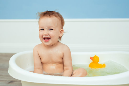 hygiene and care for young children. one year old baby bathes in the bathroom. Portrait of a cheerful laughing girl who bathes in a small bath with soapy foam