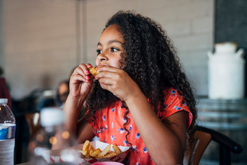 Girl eating chicken wings and french fries take out with hands