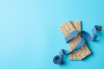 Measure tape and diet bread on blue background