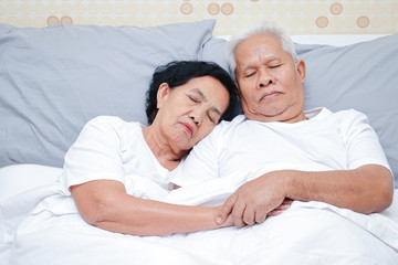 Asian elderly couple Sleep in bed in the bedroom. Senior health concepts, illness, retirement life.