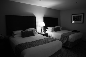 Two queen beds in an empty hotel room taken in black and white