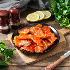 Dried macrourus caviar in a black plate on a brown wooden table. Dried or dried caviar. Healthy diet. Rustic style