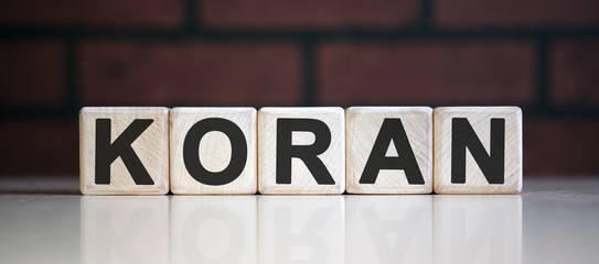 KORAN - holy book, text on wooden cubes on dark background