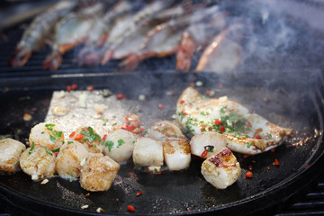 Cooking process, preparation. Prawns shrimps, squid and scallops with smoke with herbs, pepper on the grill. Summer picnic. Background image, copy space