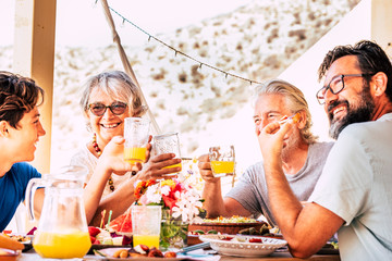 Group of happy caucasian people with different ages and generations enjoy and have fun together eating at the table - food and friendship concept with young and senior and adult cheerful family