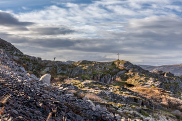Russia, Arctic, Kola Peninsula, Teriberka: view with orthodox wooden cross on rocky hill and calm Barents Sea near center of the old Russian settlement small fishing village - travel religion