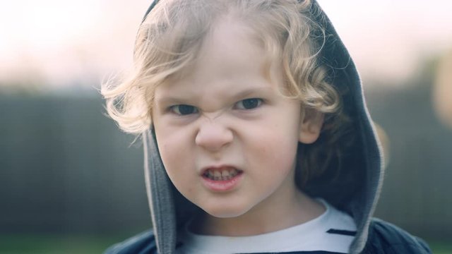 Rack focus to 4 year old boy snarling at camera trying to keep straight face