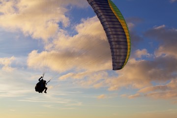 Tandem paragliding flying alone in sunset sky