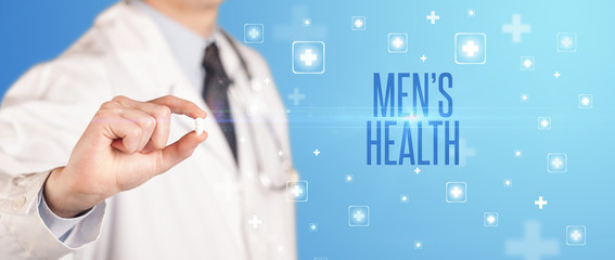 Close-up of a doctor giving a pill with MEN’S HEALTH inscription, medical concept