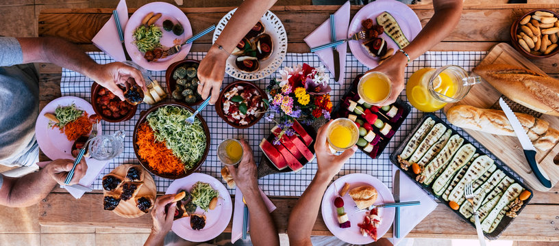 Top vertical view of table full of food and drinks and happy people friends celebrating and. enjoy together eating and having fun - concept of social distance  at home with parents in friendship