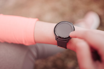 Runner using heart rate monitor training running, smartwatch checking performance or GPS. Girl athlete looking at smartwatch. Wearable technology for tracking activity. Healthy lifestyle concept.