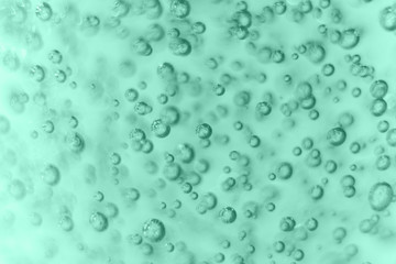 Many round bubbles of the shower gel on the mint background.