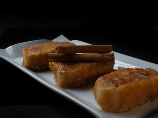 three french toast with cinnamon on white plate and dark background