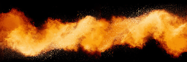 Freeze motion of orange color powder exploding on black background. 