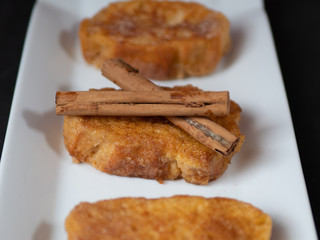 three french toast with cinnamon on white plate and dark background