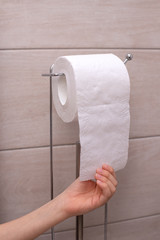 rolls of white toilet paper are piled on the toilet lid in the bathroom