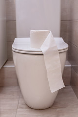 rolls of white toilet paper are piled on the toilet lid in the bathroom