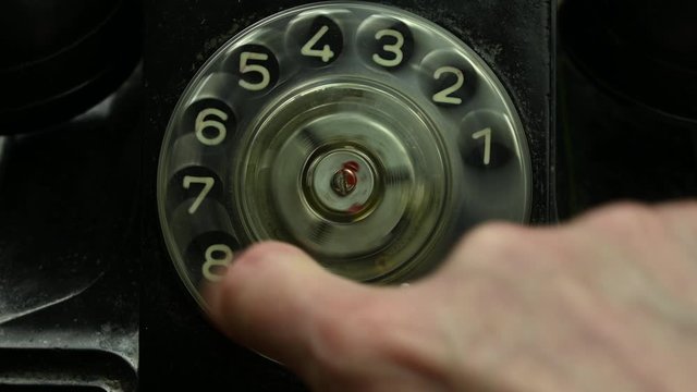 man turns dial with numbers on old phone