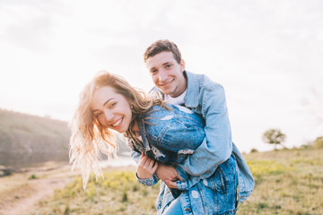 couple in love in blue jeans and white shirts in nature, where the field and rocks