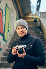 Closeup of young  man with digital camera outdoors. Young male photographer photographing nature